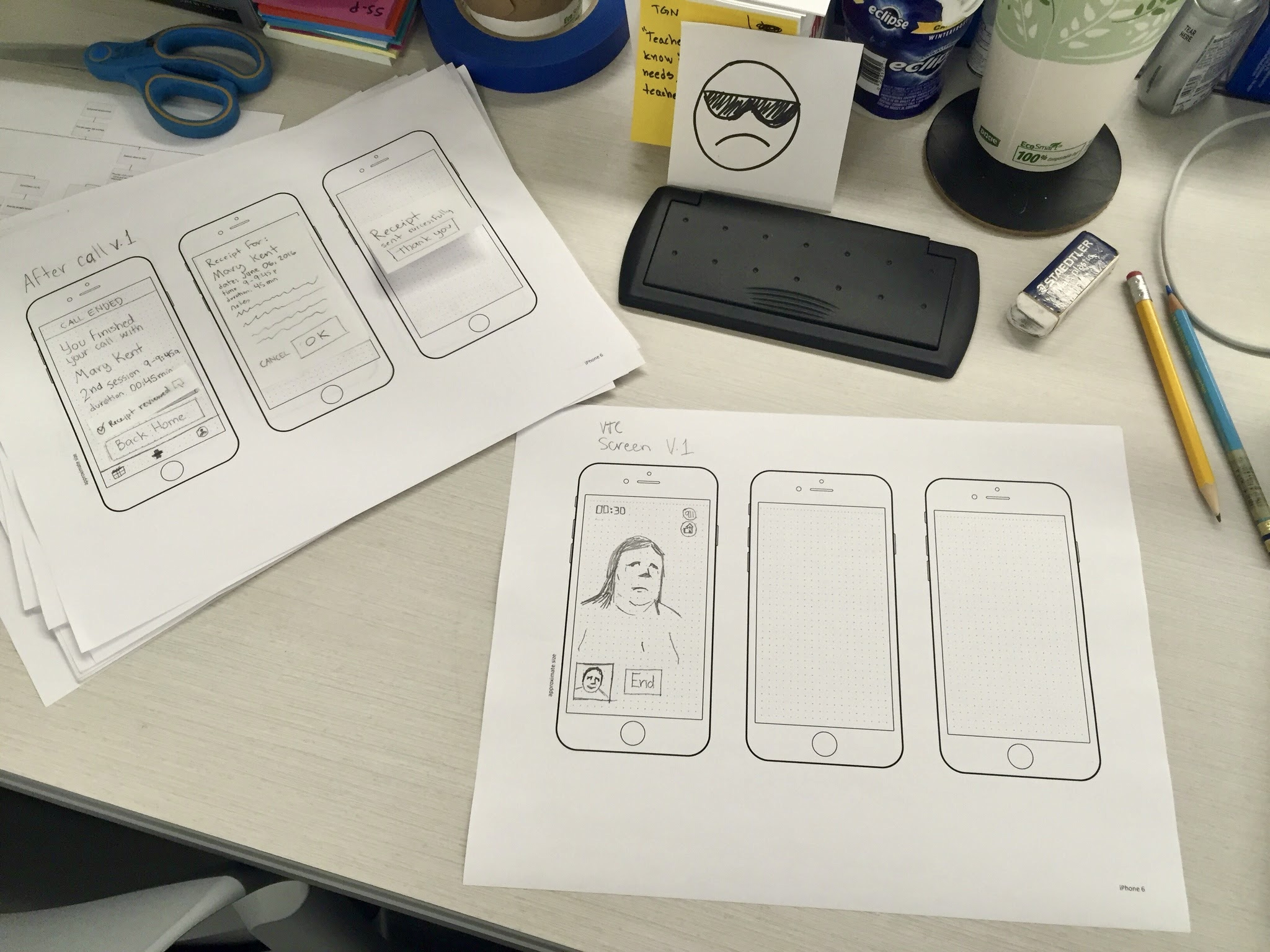 A few papers with rough sketches of the Emotilink mobile experience are on top of a desk.